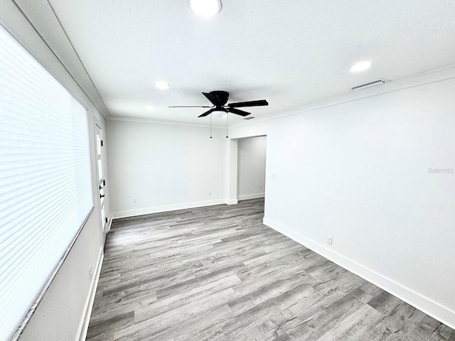 unfurnished room featuring visible vents, light wood-style floors, ornamental molding, ceiling fan, and baseboards