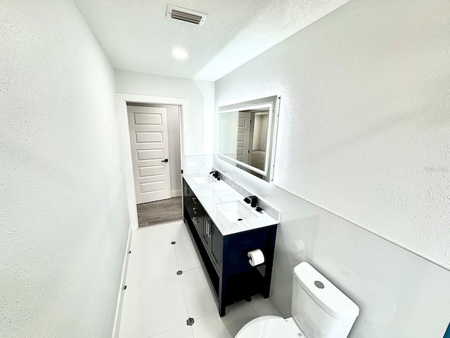 bathroom featuring double vanity, a textured ceiling, visible vents, and a sink