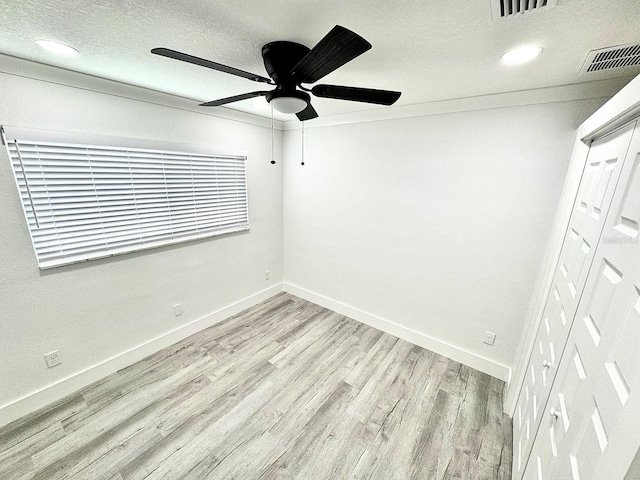 unfurnished bedroom with a closet, visible vents, light wood-style flooring, a textured ceiling, and baseboards