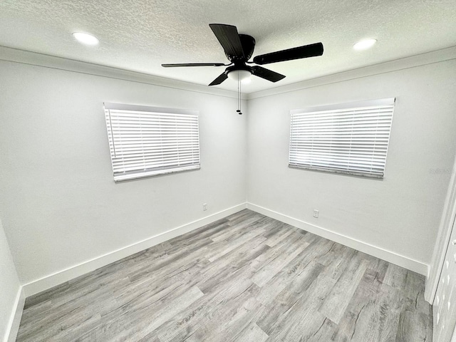 empty room with a textured ceiling, ceiling fan, light wood finished floors, and baseboards