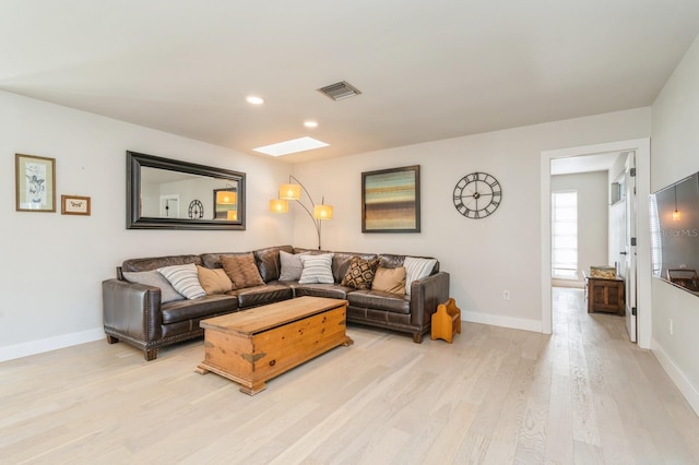 living room with a skylight and light hardwood / wood-style floors