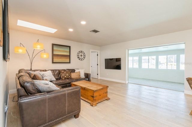 living room featuring a skylight and light wood-type flooring