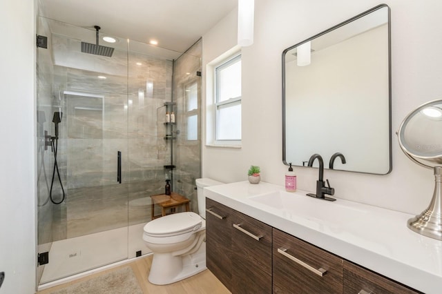 bathroom with a shower with door, vanity, wood-type flooring, and toilet