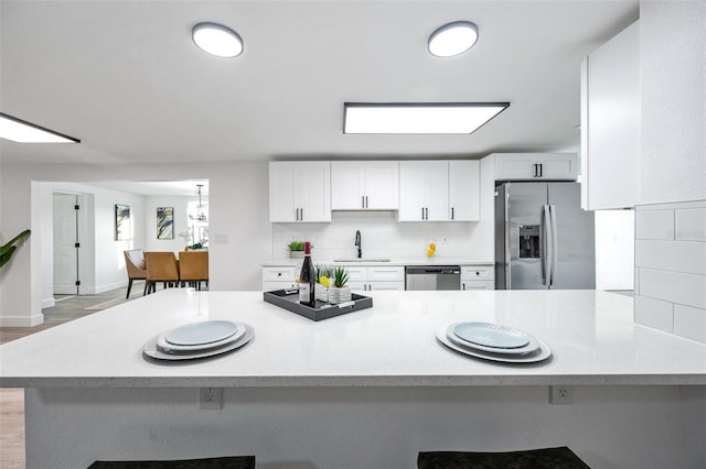 kitchen featuring sink, white cabinetry, appliances with stainless steel finishes, a kitchen breakfast bar, and kitchen peninsula