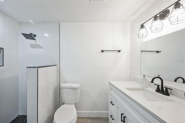 bathroom featuring hardwood / wood-style floors, vanity, a tile shower, and toilet