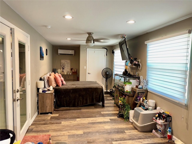 bedroom with ceiling fan, light hardwood / wood-style flooring, and a wall unit AC