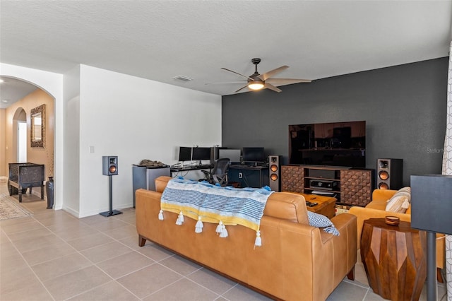 tiled living room featuring ceiling fan and a textured ceiling