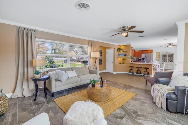 living area with crown molding, baseboards, visible vents, and a ceiling fan