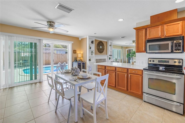 kitchen featuring light tile patterned floors, stainless steel appliances, visible vents, light countertops, and backsplash