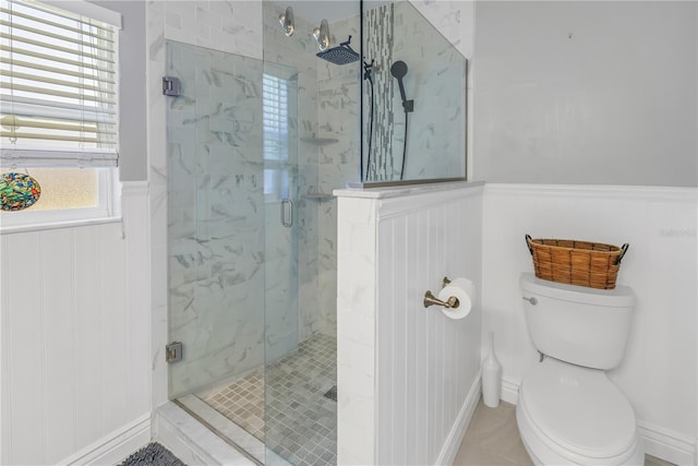 bathroom with toilet, a marble finish shower, and wainscoting