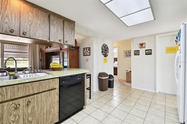 kitchen with light tile patterned flooring, sink, a skylight, white refrigerator, and black dishwasher