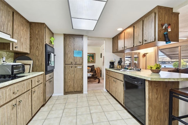 kitchen with sink, a breakfast bar, black appliances, light tile patterned flooring, and kitchen peninsula