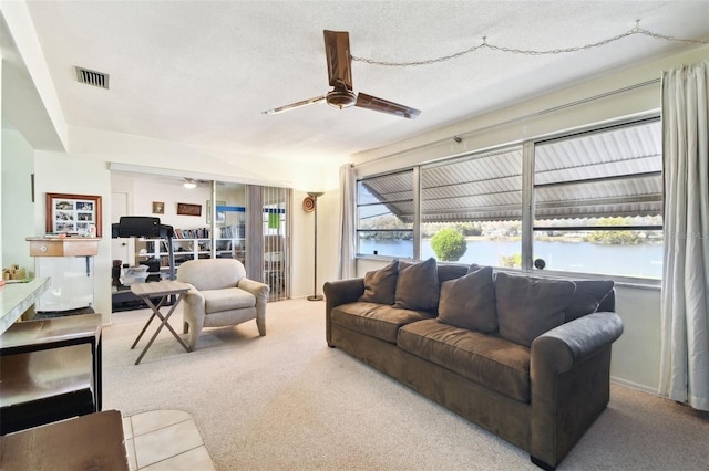 living room featuring a water view, light colored carpet, and ceiling fan