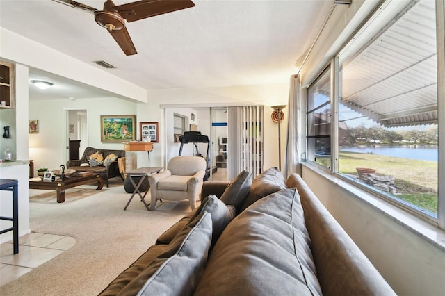 carpeted living room featuring a water view and ceiling fan