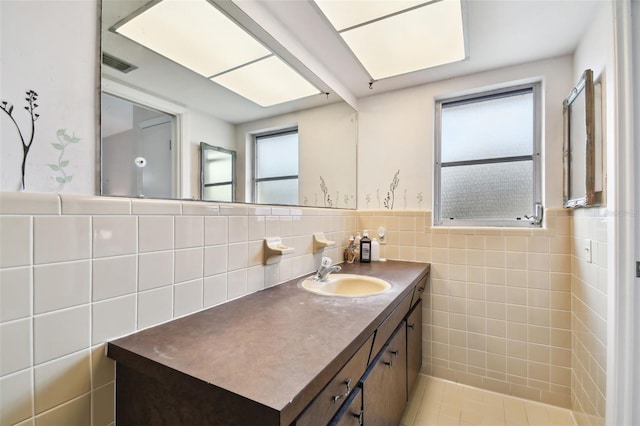 bathroom featuring a healthy amount of sunlight, tile walls, and vanity