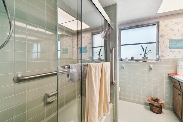 bathroom featuring vanity, combined bath / shower with glass door, and tile walls