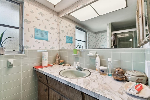 bathroom featuring walk in shower, vanity, a skylight, and tile walls