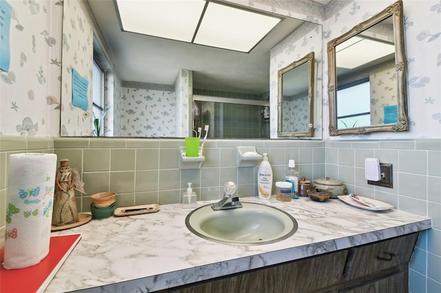 bathroom with a shower with door, vanity, and tile walls