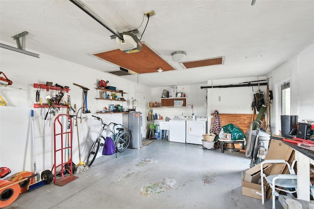 garage with a workshop area, a garage door opener, electric water heater, and washer and dryer