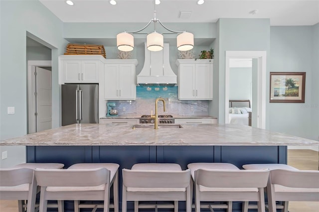 kitchen featuring white cabinetry, a large island, high end fridge, and custom range hood