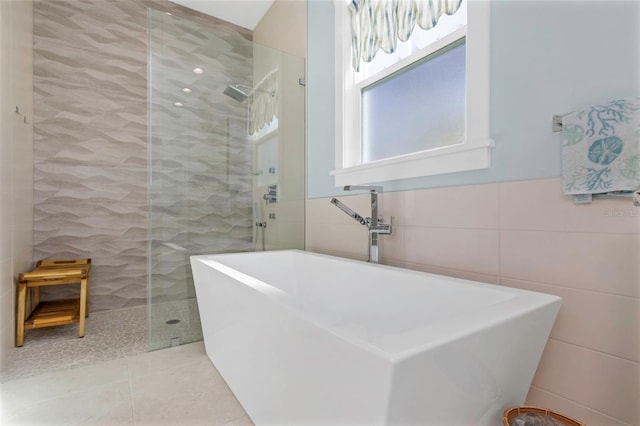 bathroom featuring tile patterned floors, separate shower and tub, sink, and tile walls