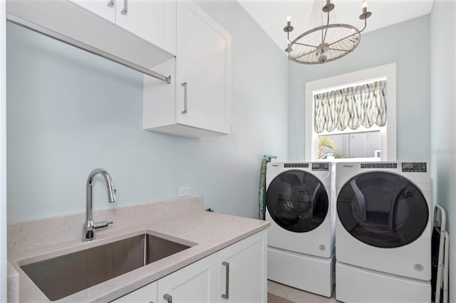 laundry area with cabinets, a notable chandelier, sink, and washing machine and clothes dryer