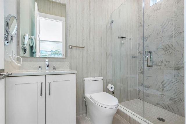 bathroom with a wealth of natural light, a shower with shower door, tile walls, vanity, and toilet