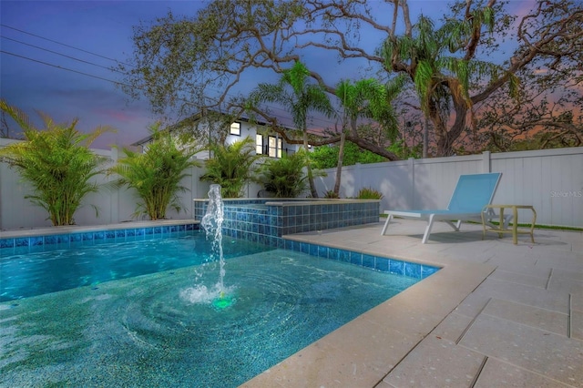 pool at dusk featuring pool water feature