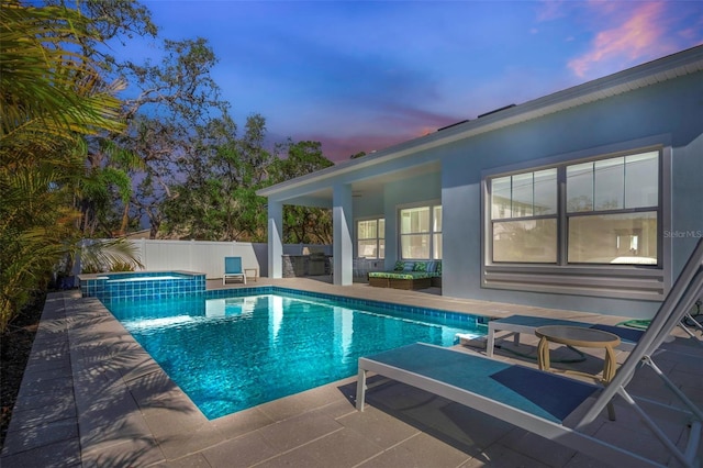 pool at dusk with an in ground hot tub and a patio