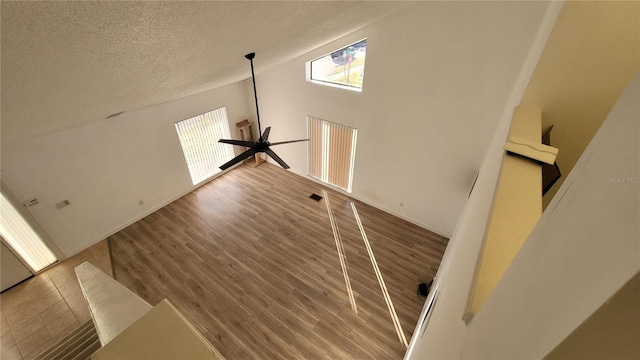 unfurnished living room with wood-type flooring, plenty of natural light, ceiling fan, and a textured ceiling