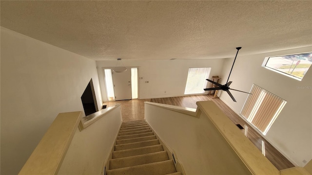 staircase featuring hardwood / wood-style floors and a textured ceiling