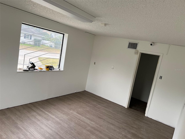 spare room featuring dark wood-type flooring and a textured ceiling