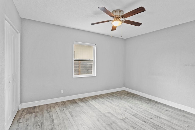 unfurnished room featuring light wood finished floors, ceiling fan, baseboards, and a textured ceiling