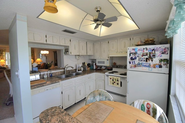 kitchen with dark countertops, visible vents, a sink, white appliances, and under cabinet range hood