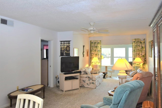 carpeted living room featuring a ceiling fan, visible vents, and a textured ceiling