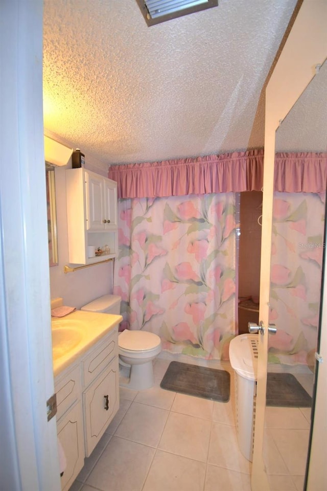 full bathroom with a textured ceiling, vanity, toilet, and tile patterned floors