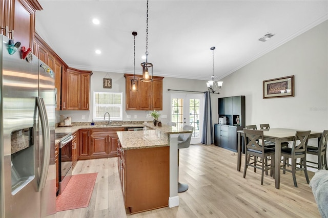 kitchen featuring sink, appliances with stainless steel finishes, light stone countertops, a kitchen island, and decorative light fixtures