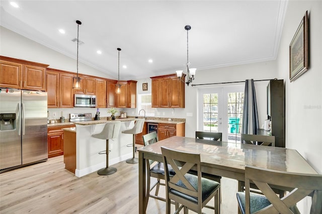 kitchen featuring a breakfast bar area, hanging light fixtures, a center island, stainless steel appliances, and light hardwood / wood-style flooring