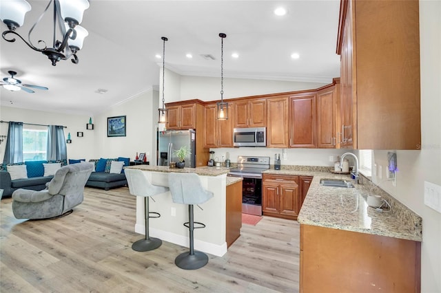 kitchen featuring a kitchen island, sink, light stone counters, stainless steel appliances, and light hardwood / wood-style flooring