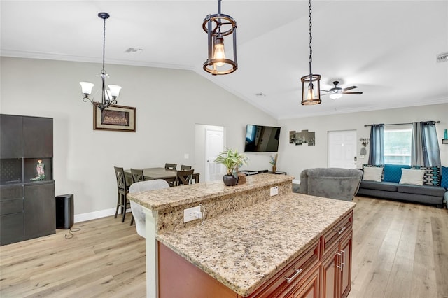 kitchen featuring lofted ceiling, crown molding, light stone counters, decorative light fixtures, and light hardwood / wood-style flooring