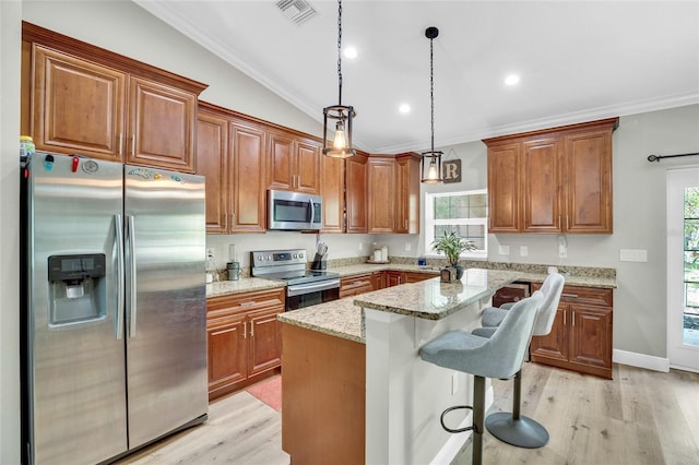 kitchen featuring a kitchen island, appliances with stainless steel finishes, decorative light fixtures, a kitchen breakfast bar, and light stone countertops