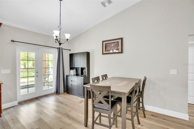 dining room featuring crown molding, a chandelier, light wood-type flooring, and french doors