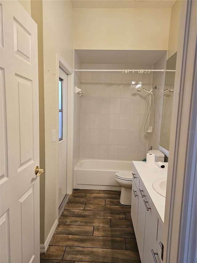 full bathroom featuring hardwood / wood-style flooring, vanity, tiled shower / bath, and toilet