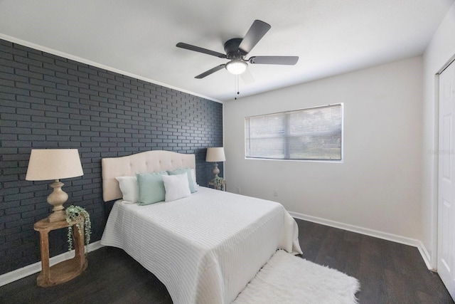 bedroom with dark hardwood / wood-style flooring, ceiling fan, and brick wall