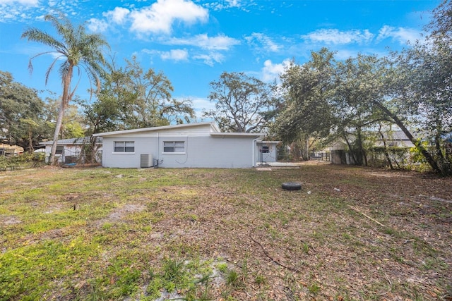 back of house with central AC and a lawn