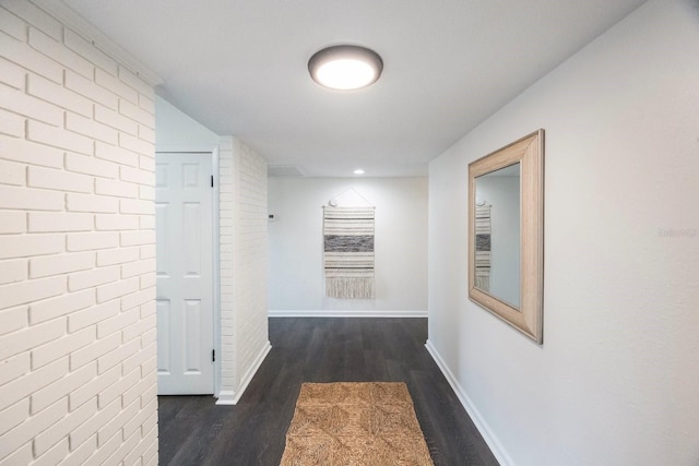 hall with brick wall and dark hardwood / wood-style floors