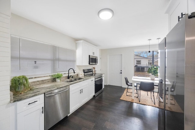 kitchen featuring white cabinetry, stainless steel appliances, decorative light fixtures, and dark stone counters