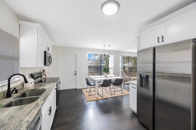 kitchen with white cabinetry, stainless steel appliances, sink, and hanging light fixtures