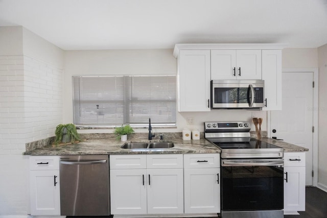 kitchen with white cabinetry, stainless steel appliances, sink, and dark stone counters