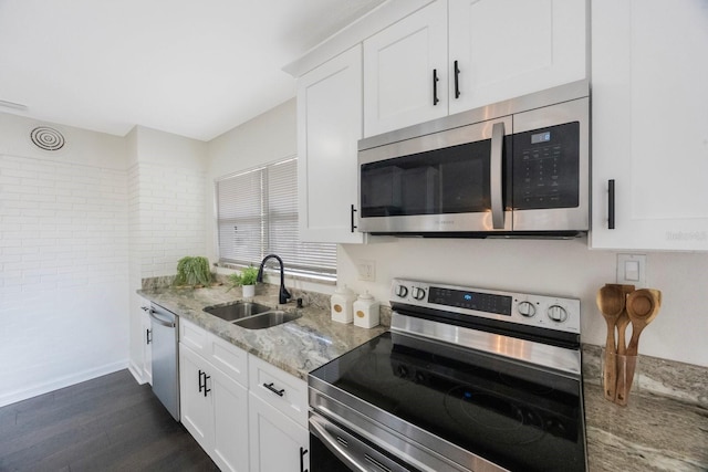 kitchen featuring dark wood-type flooring, sink, light stone counters, appliances with stainless steel finishes, and white cabinets